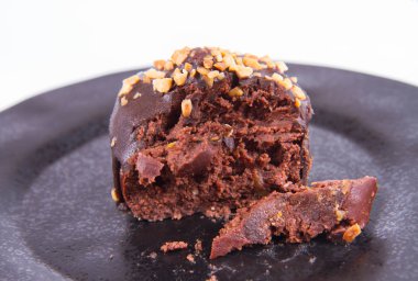 Çikolata ve fındık kısmen yemiş, beyaz bir arka plan üzerinde siyah bir plaka üzerinde romlu süslenmiş