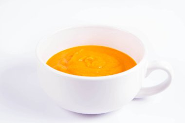 Beyaz arka planda bir kasede balkabağı çorbası