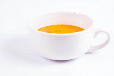 Beyaz arka planda bir kasede balkabağı çorbası