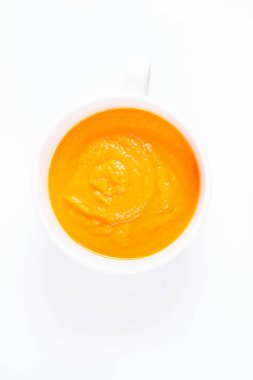 Beyaz arka planda bir kasede balkabağı çorbası