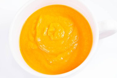 Beyaz arka planda bir kasede balkabağı çorbası