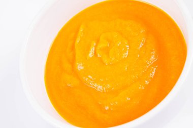 Beyaz arka planda bir kasede balkabağı çorbası