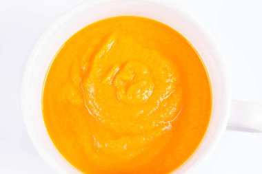 Beyaz arka planda bir kasede balkabağı çorbası