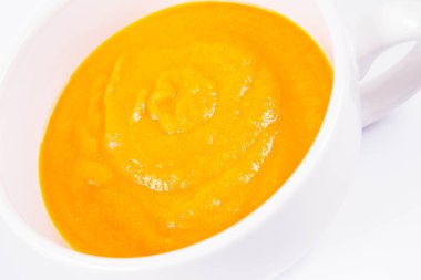 Beyaz arka planda bir kasede balkabağı çorbası