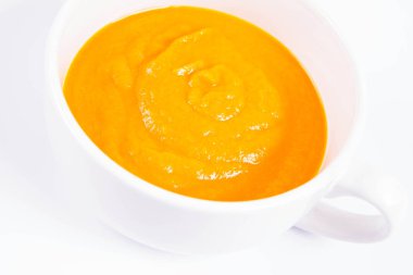 Beyaz arka planda bir kasede balkabağı çorbası