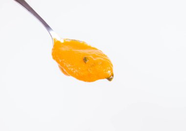 Bir kaşık beyaz bir arka plan üzerinde balkabağı çorbası