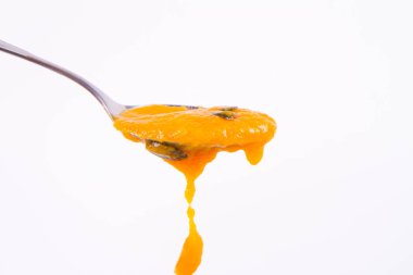 Bir kaşık beyaz bir arka plan üzerinde kabak çekirdeği ile dekore edilmiş balkabağı çorbası