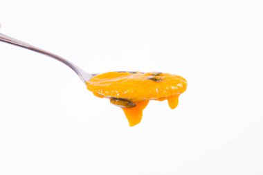 Bir kaşık beyaz bir arka plan üzerinde balkabağı çorbası