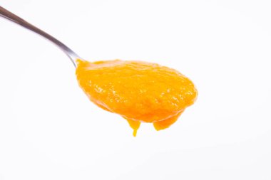 Bir kaşık beyaz bir arka plan üzerinde balkabağı çorbası