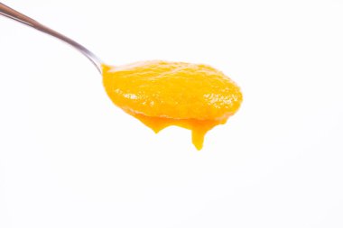 Bir kaşık beyaz bir arka plan üzerinde balkabağı çorbası