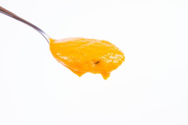 Bir kaşık beyaz bir arka plan üzerinde balkabağı çorbası