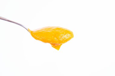 Bir kaşık beyaz bir arka plan üzerinde balkabağı çorbası