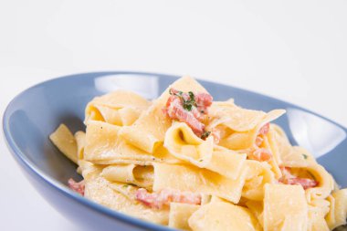 Beyaz zemin üzerinde mavi bir tabakta pappardelle Carbonara