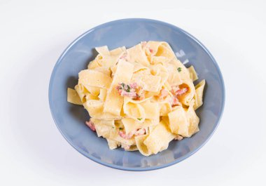Beyaz zemin üzerinde mavi bir tabakta pappardelle Carbonara