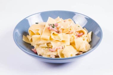Beyaz zemin üzerinde mavi bir tabakta pappardelle Carbonara