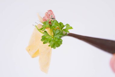 Pappardelle Carbonara bazı maydanoz üzerinde beyaz bir arka plan üzerinde bir çatalı ile