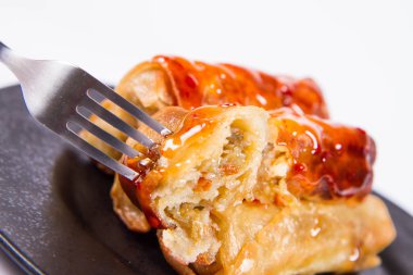 Çince geleneksel tatlı ve ekşi sos ile bir çatalla yenir bir siyah plaka üzerinde Çin böreği