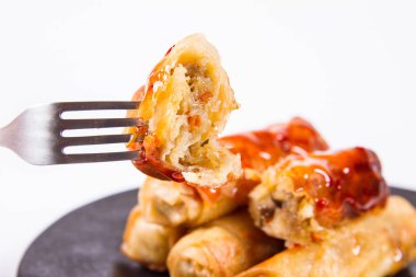 Çince geleneksel tatlı ve ekşi sos ile bir çatalla yenir bir siyah plaka üzerinde Çin böreği