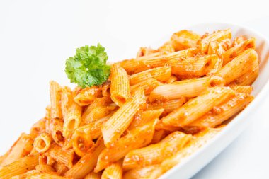 Beyaz zemin üzerinde bir tabakta maydanoz penne pesto ile süslenmiş