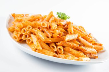 Beyaz zemin üzerinde bir tabakta maydanoz penne pesto ile süslenmiş