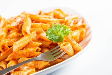 Beyaz zemin üzerinde bir çatal ile yemiş bir plaka üzerinde maydanoz penne pesto ile süslenmiş