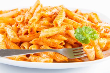 Beyaz zemin üzerinde bir çatal ile yemiş bir plaka üzerinde maydanoz penne pesto ile süslenmiş