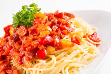 Beyaz zemin üzerinde bir plaka üzerinde taze maydanoz ile süslenmiş soslu spagetti