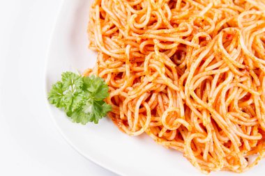 Beyaz zemin üzerinde bir tabakta maydanoz spagetti pesto ile süslenmiş