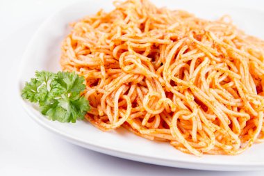Beyaz zemin üzerinde bir tabakta maydanoz spagetti pesto ile süslenmiş