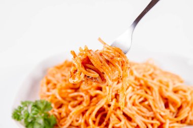 Beyaz zemin üzerinde bir çatal ile yemiş maydanoz spagetti pesto rosso ile süslenmiş