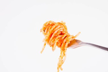 Pesto rosso üzerinde beyaz bir arka plan üzerinde bir çatalı spagetti