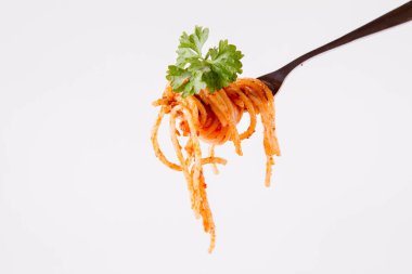 Beyaz zemin üzerine maydanoz spagetti pesto rosso üzerinde bir çatal ile süslenmiş