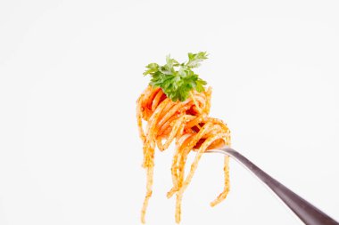 Beyaz zemin üzerine maydanoz spagetti pesto rosso üzerinde bir çatal ile süslenmiş