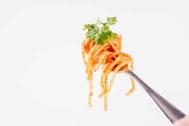 Beyaz zemin üzerine maydanoz spagetti pesto rosso üzerinde bir çatal ile süslenmiş