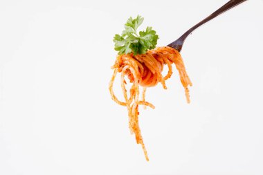 Beyaz zemin üzerine maydanoz spagetti pesto rosso üzerinde bir çatal ile süslenmiş