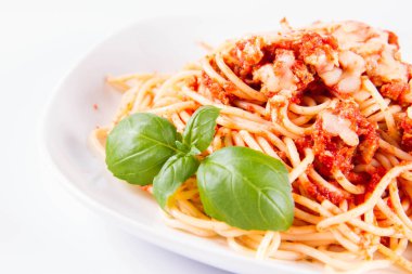 Beyaz arka planda fesleğenle süslenmiş erimiş parmesan peynirli spagetti bolonez.