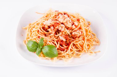 Beyaz arka planda fesleğenle süslenmiş erimiş parmesan peynirli spagetti bolonez.