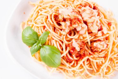 Beyaz arka planda fesleğenle süslenmiş erimiş parmesan peynirli spagetti bolonez.