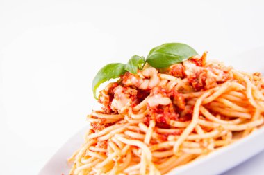 Beyaz arka planda fesleğenle süslenmiş erimiş parmesan peynirli spagetti bolonez.