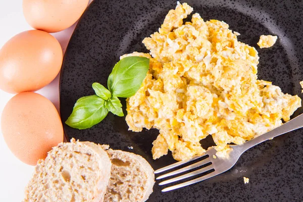炒鸡蛋 一些新鲜的鸡蛋和全麦面包 以及一个叉子 用罗勒装饰 在白色的背景 — 图库照片