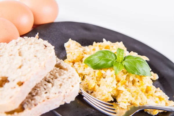 バジル 白の背景に飾られたスクランブルエッグ いくつかの新鮮な卵と全粒粉のパン フォーク — ストック写真