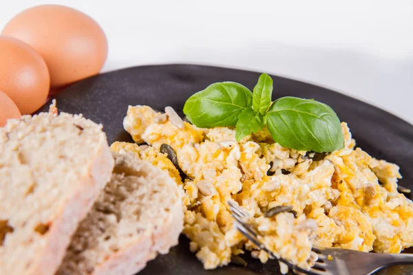 バジル 白の背景に飾られたヒマワリやカボチャの種 いくつかの新鮮な卵と フォークで食べる全粒粉のパンとスクランブルエッグ — ストック写真