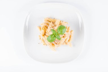 Taze fesleğen ile süslenmiş bir tabakta pastırma ile krema sos ile penne makarna - beyaz