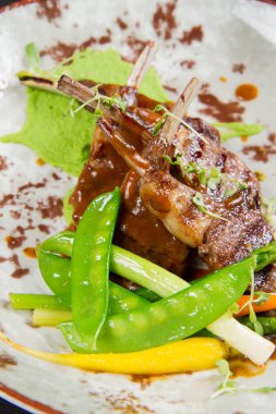 Kuzu pirzolası kar bezelye, havuç, siyah bir arka plan üzerinde kuşkonmaz, pırasa ve bezelye püre ile