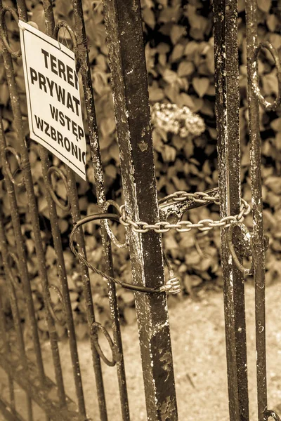 Gate closed with a chain , with a plaque saying \'private property no trespassing\' in polish