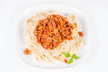 Beyaz arka planda taze fesleğen ile süslenmiş bir tabaküzerinde spagetti bolonez