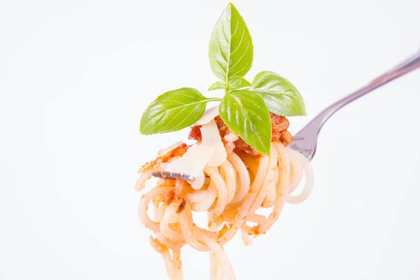 白い背景にフォークにパルメザンチーズと新鮮なバジルで飾られたプレート上のスパゲッティボロネーゼ — ストック写真