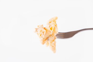 Çatalla yenen makarna. Beyaz arka planda beyaz krema soslu makarna.