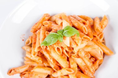 Peynirli makarna ve fesleğenle süslenmiş güneşte kurutulmuş domates.