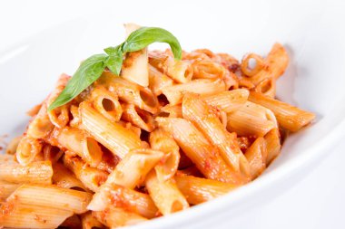 Peynirli makarna ve fesleğenle süslenmiş güneşte kurutulmuş domates.